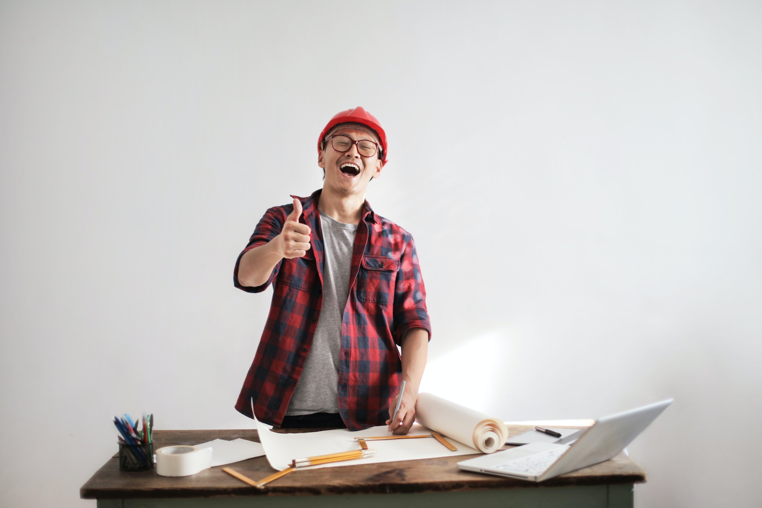 A person with a thumbs-up and a construction helmet, making modifications to a construction drawing