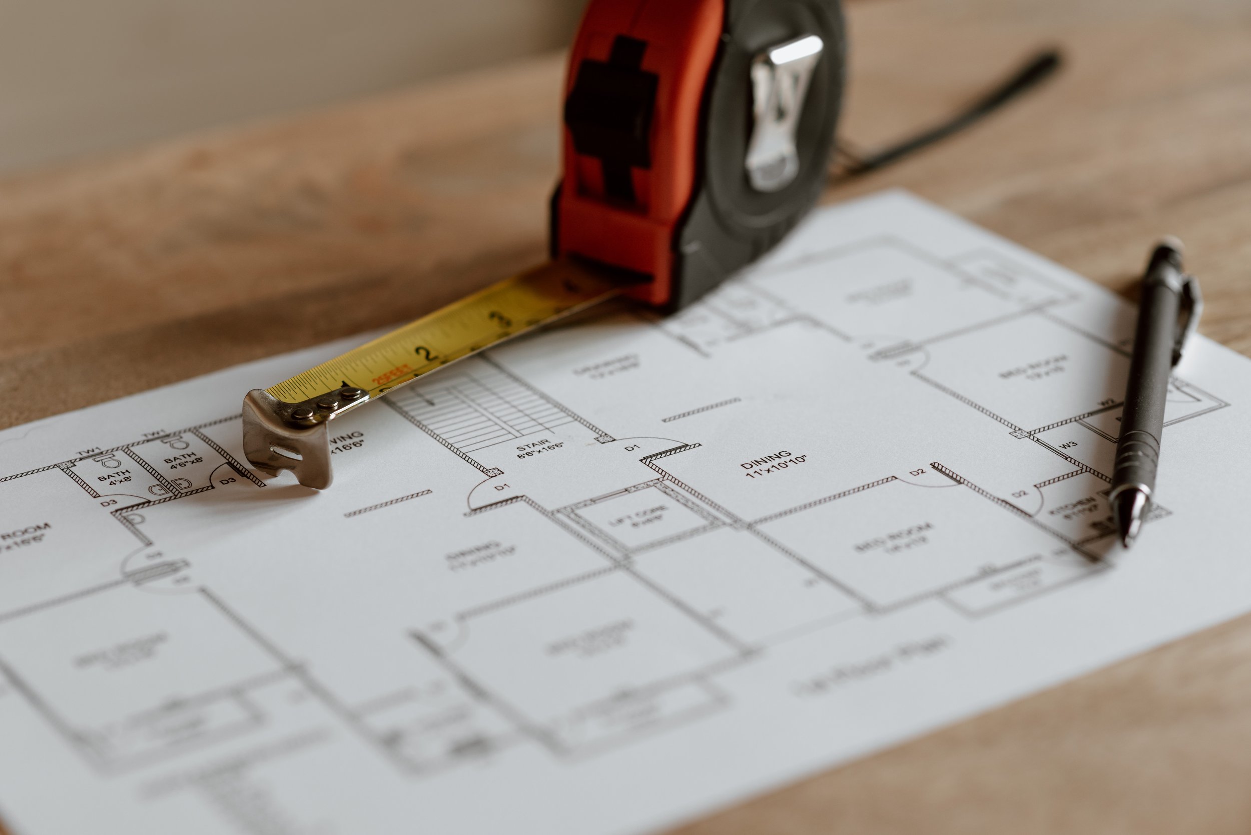 A tape measure that is on a house construction plan.