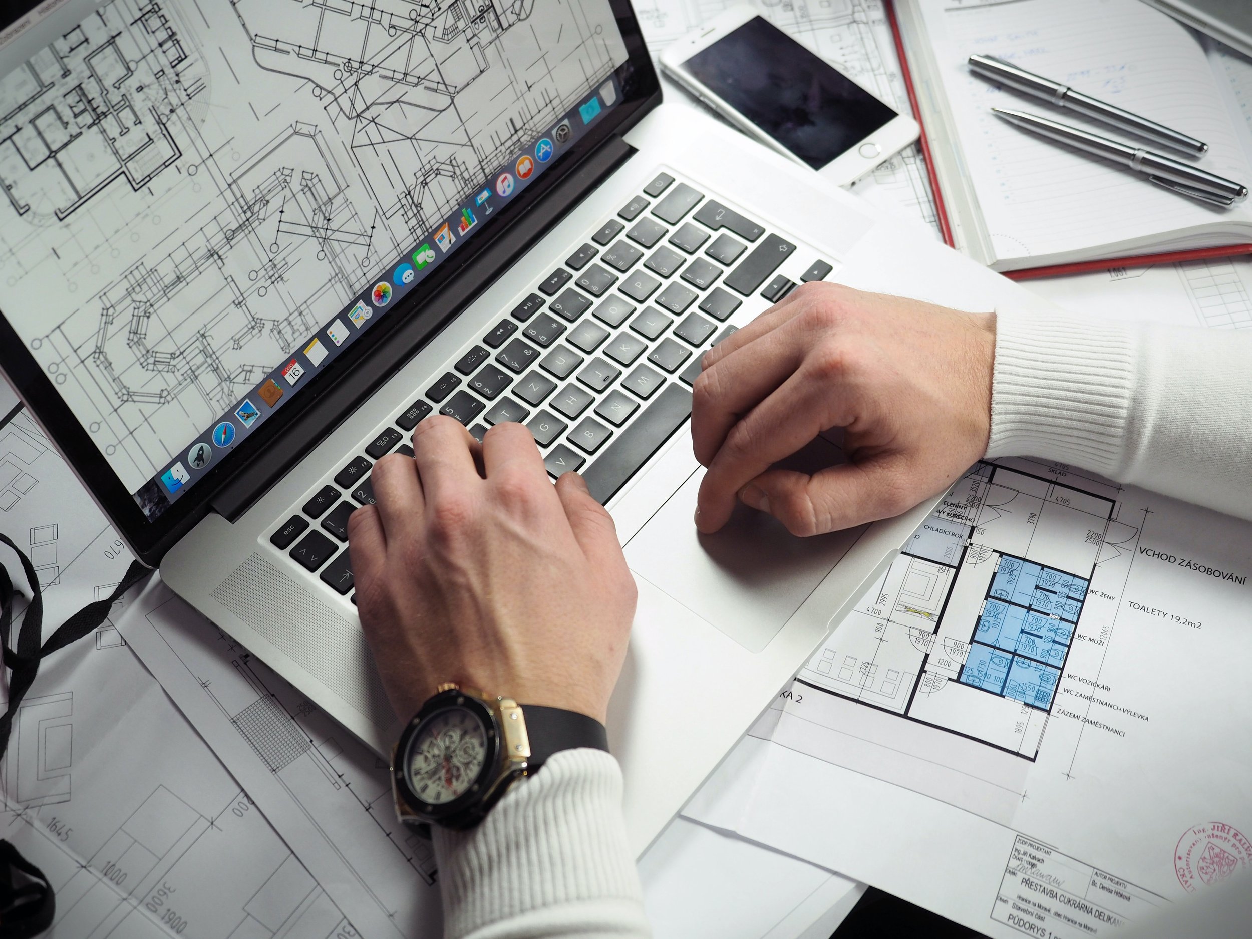 A person's hands on a laptop with a house modification plan open.